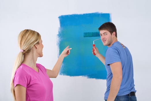 happy young couple paint in green and blue color white wall of their new home