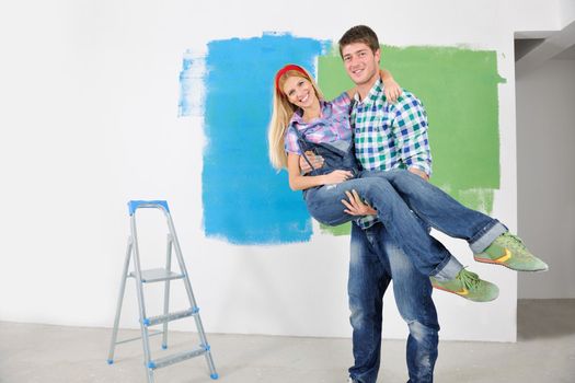 happy young couple paint in green and blue color white wall of their new home