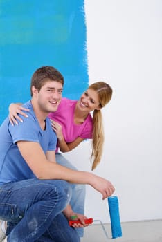 happy young couple paint in green and blue color white wall of their new home