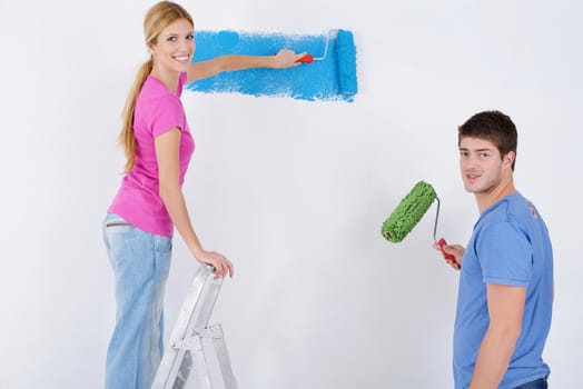 happy young couple paint in green and blue color white wall of their new home