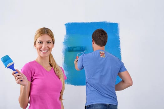 happy young couple paint in green and blue color white wall of their new home