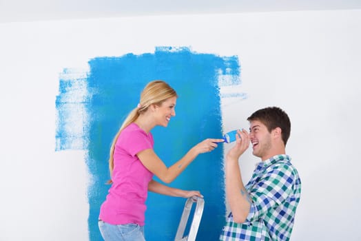 happy young couple paint in green and blue color white wall of their new home