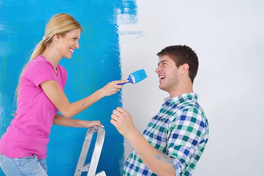 happy young couple paint in green and blue color white wall of their new home