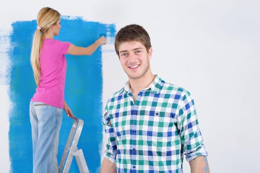 happy young couple paint in green and blue color white wall of their new home