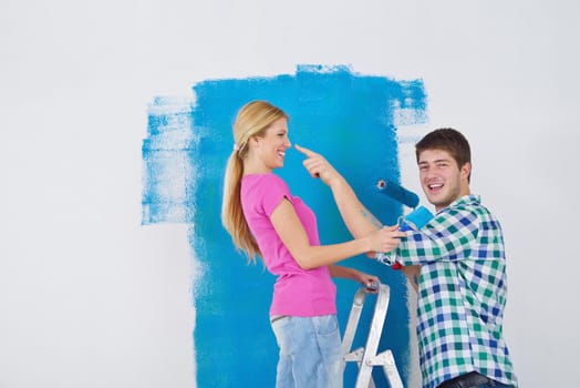 happy young couple paint in green and blue color white wall of their new home