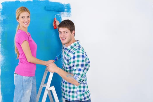 happy young couple paint in green and blue color white wall of their new home