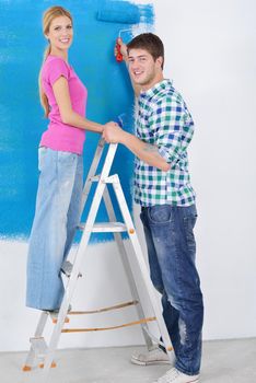 happy young couple paint in green and blue color white wall of their new home