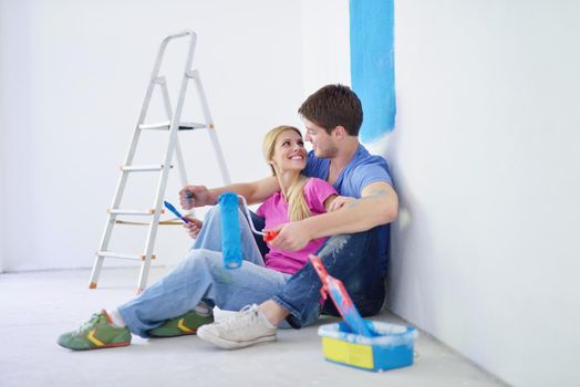 happy young couple relax after painting white wall in green and blue color in their new home