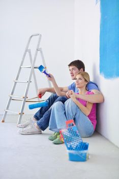 happy young couple relax after painting white wall in green and blue color in their new home