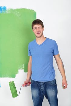 handsome young man paint in blue and green color  white wall of new home