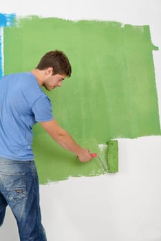 handsome young man paint in blue and green color  white wall of new home