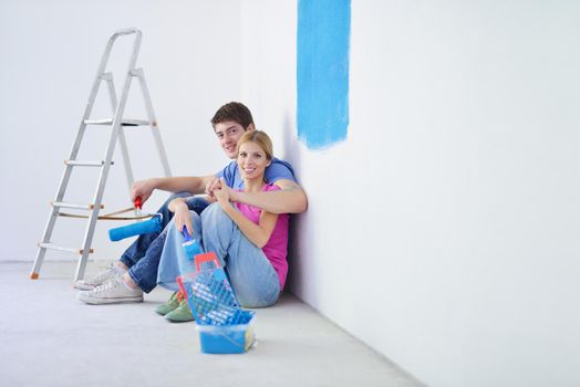 happy young couple relax after painting white wall in green and blue color in their new home