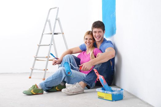 happy young couple relax after painting white wall in green and blue color in their new home