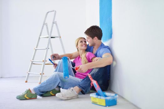 happy young couple relax after painting white wall in green and blue color in their new home