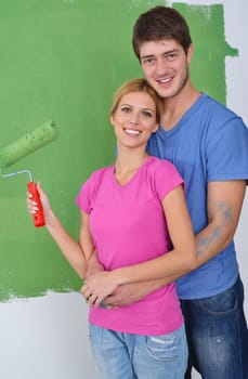 happy young couple paint in green and blue color white wall of their new home