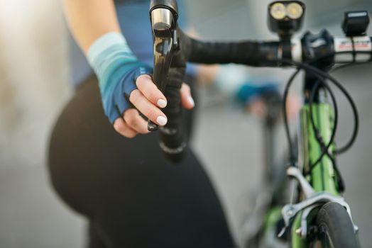 Close up shot of hand on handlebar. Professional female cyclist standing with her bike outdoors on a daytime. Sport, biking, people concept. Selective focus