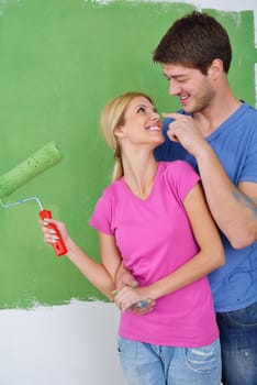 happy young couple paint in green and blue color white wall of their new home