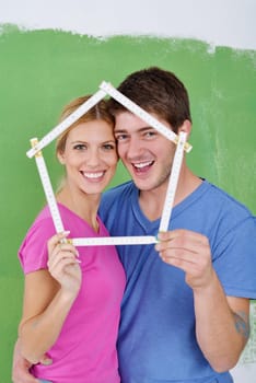 happy young couple paint in green and blue color white wall of their new home