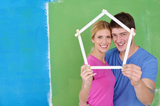 happy young couple paint in green and blue color white wall of their new home