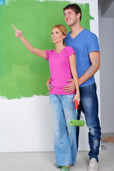 happy young couple paint in green and blue color white wall of their new home