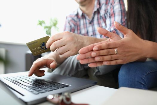 Close-up of wife and husband want to buy something online via credit card. Open laptop on desk and man typing on keyboard. Online shopping, remote concept