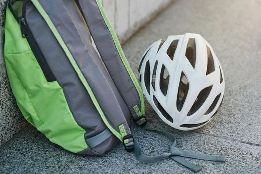 Close up of backpack and white hemet on granite surface. Cycling, extreme and active lifestyle concept