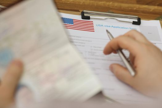 Close-up of person filling visa application forms holding personal passport. Standard process to access country. Immigration, permission, embassy concept