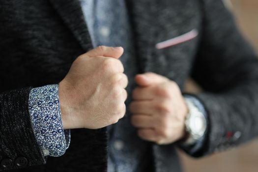Close-up of business man touching his stylish jacket and feel confident in himself. Person prepare for going out, look fashionable. Style, fashion concept