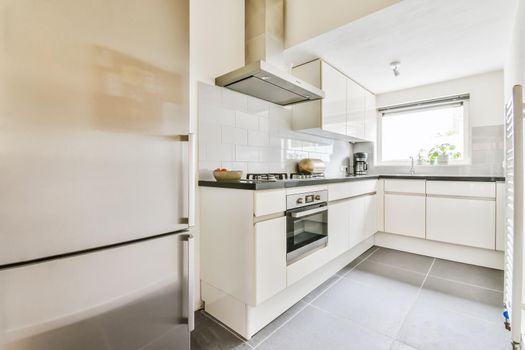 Adorable kitchen area with modern oven and refrigerator