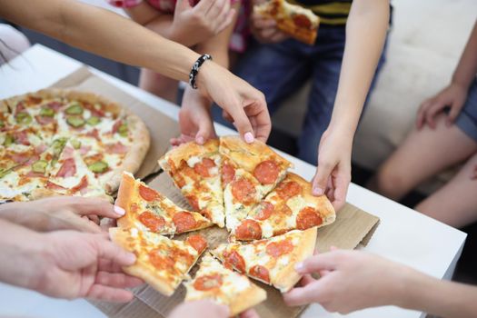 Close-up of hands of big company take piece of round shaped pizza. Hot smelly pizza with tomatoes and cheese. Fast food, takeaway, lunch, unhealthy concept