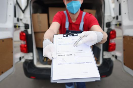 Portrait of man in uniform and face mask give delivery receipt paper to receiver to sign. Worker ask to fill information paper. Delivery service concept