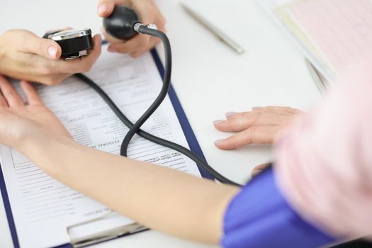 Close-up of doctor measuring patients blood pressure with tonometer tool in office. Planned checkup at family doctor. Medicine, healthcare, help concept