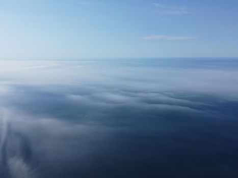 Abstract nature summer or spring ocean sea background. Small waves on water surface in motion blur with bokeh lights from sunrise.