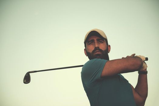 golfer hitting long shot with driver on course at beautiful sunset