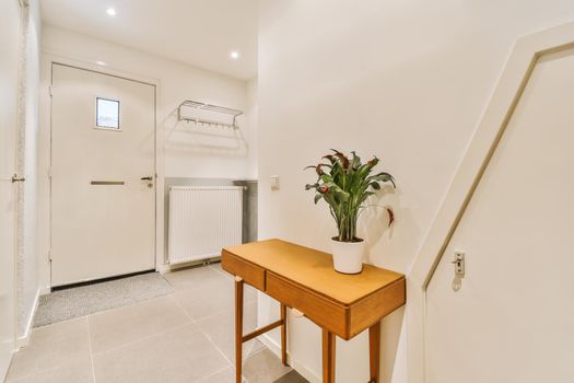 Wide entrance hall with a coat rack and a wooden cabinet on high legs