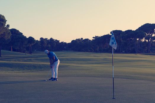 golf player hitting ball  with driver on course at beautiful sunset