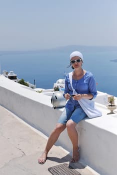 Beautiful young Greek woman in fashion clothes have fun at n the streets of Oia, Santorini, Greece