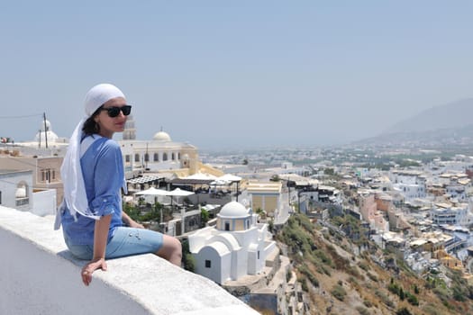 Beautiful young Greek woman in fashion clothes have fun at n the streets of Oia, Santorini, Greece