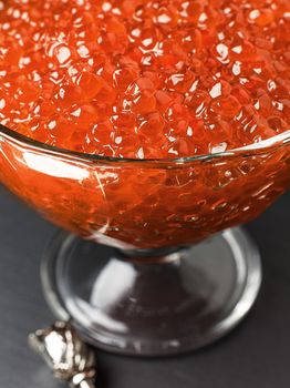 Red caviar in a glass bowl with silver decoration.