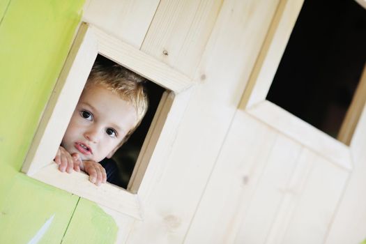 happy cute child in a wooden window at playground