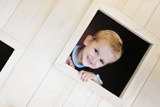 happy cute child in a wooden window at playground