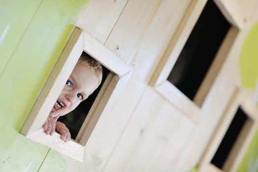 happy cute child in a wooden window at playground