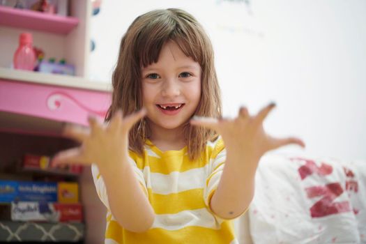 cute little girl at home painting with hands funny no tooth smile