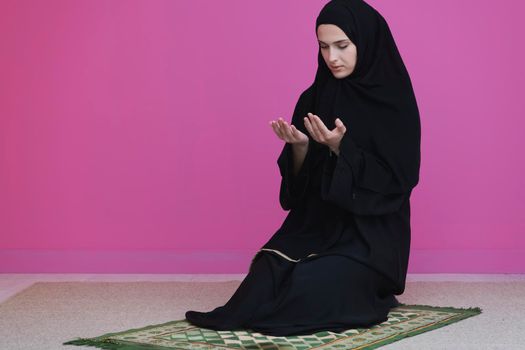 Muslim woman in namaz praying to Allah, God. Muslim woman on the carpet praying in traditional middle eastern clothes, Woman in Hijab