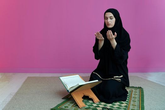 Middle eastern woman praying and reading the holy Quran, public item of all muslims. Education concept of Muslim woman studying The holy Quran at home or mosque in ramadan month.