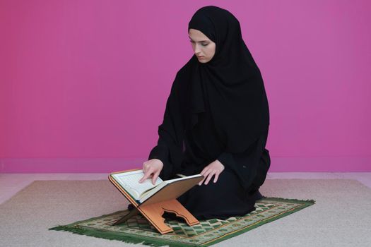 Middle eastern woman praying and reading the holy Quran, public item of all muslims. Education concept of Muslim woman studying The holy Quran at home or mosque in ramadan month.