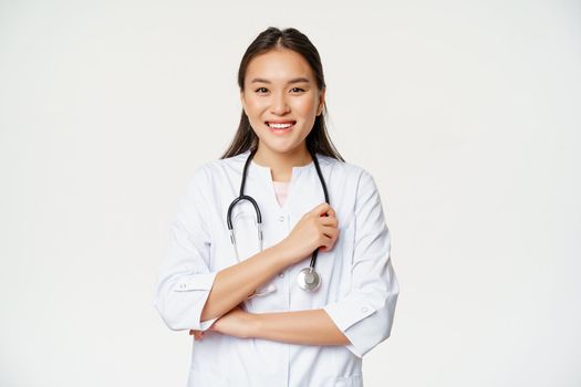 Healthcare and hospital concept. Smiling asian doctor, female nurse in uniform, looking happy at camera, standing over white background.