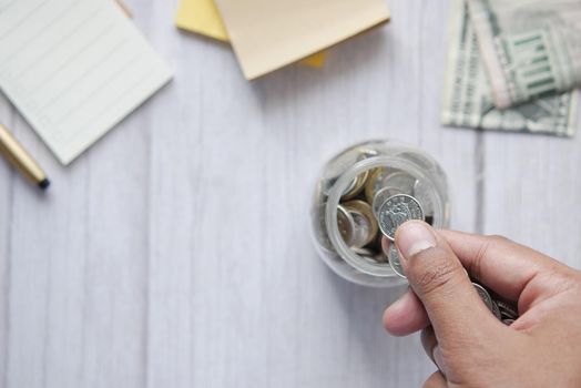 young man saving coins in a jar white sited .