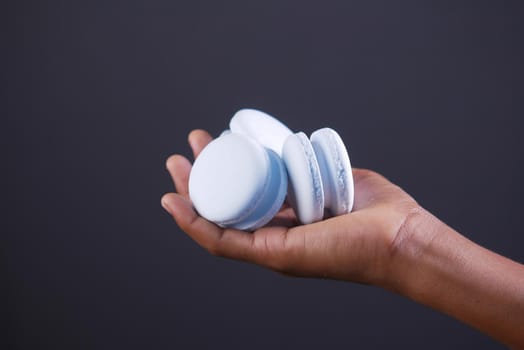 hand hold macaroon against gray background .