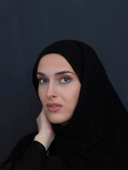 Portrait of modern young muslim woman in black abaya. Arab girl wearing traditional clothes and posing in front of black chalkboard. Representing modern and rich arabic lifestyle